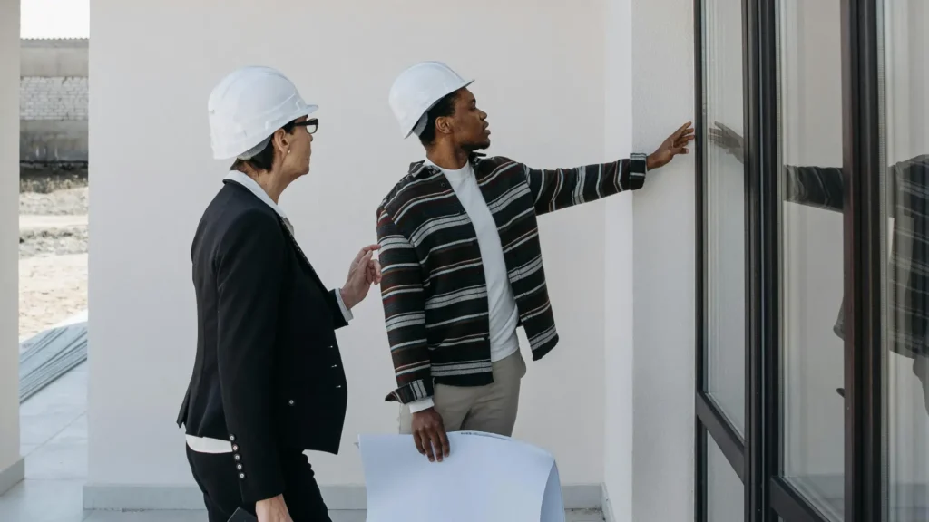 Inspectors discussing exterior wall during HQS inspection for Housing Choice Voucher compliance