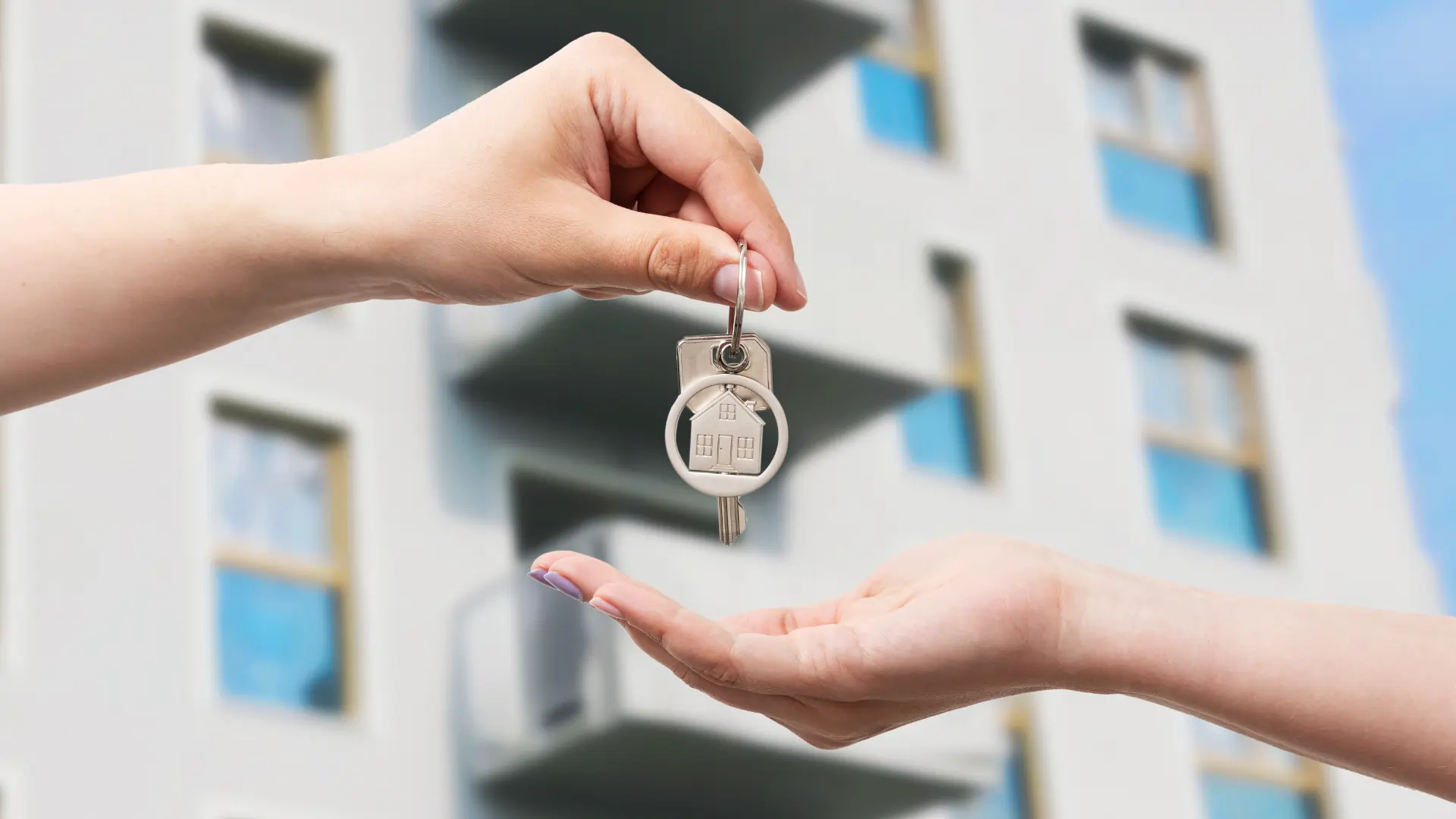 Handing over apartment keys in front of a multifamily building, symbolizing Rental Property Inspection Laws