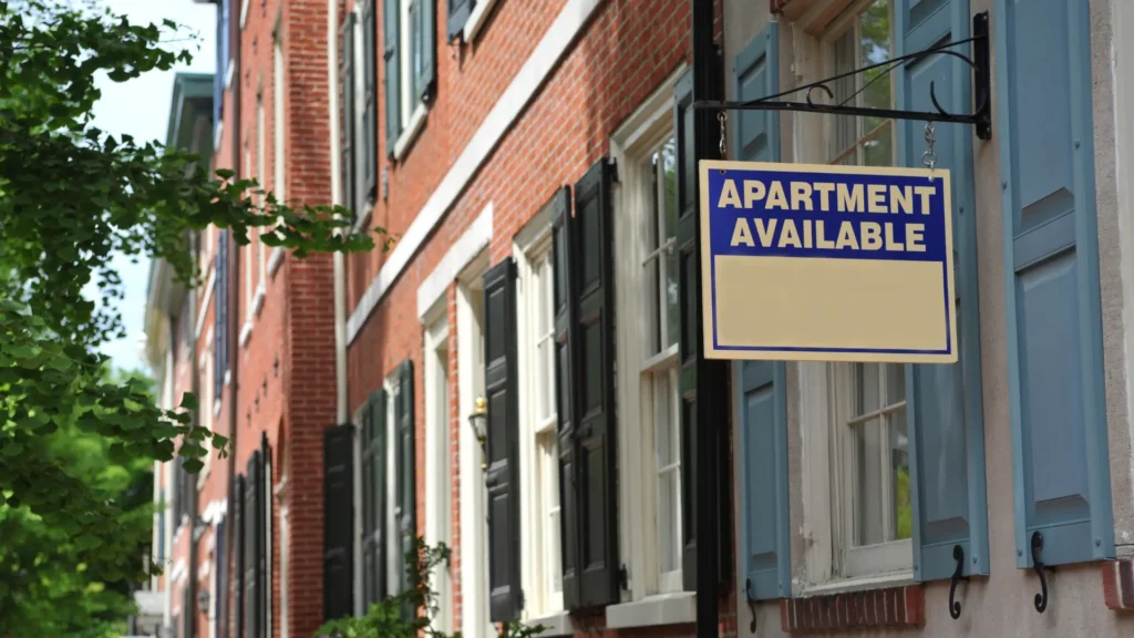 Apartment available sign hanging outside rental building, emphasizing Rental Property Inspection Laws.