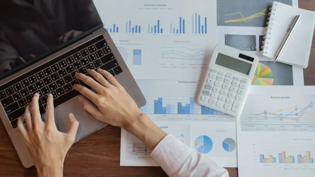 Hands on laptop with calculator and charts analyzing CapEx ratio in real estate