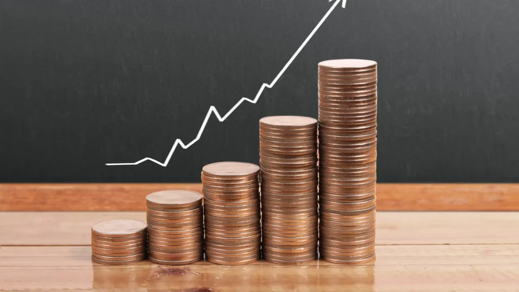 Stacked coins showing capital growth with an upward financial chart in the background
