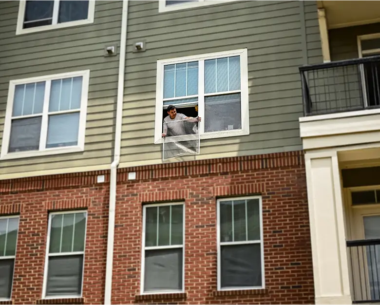 Exterior Apartment Renovations in Progress Worker performing apartment renovations from second-story window