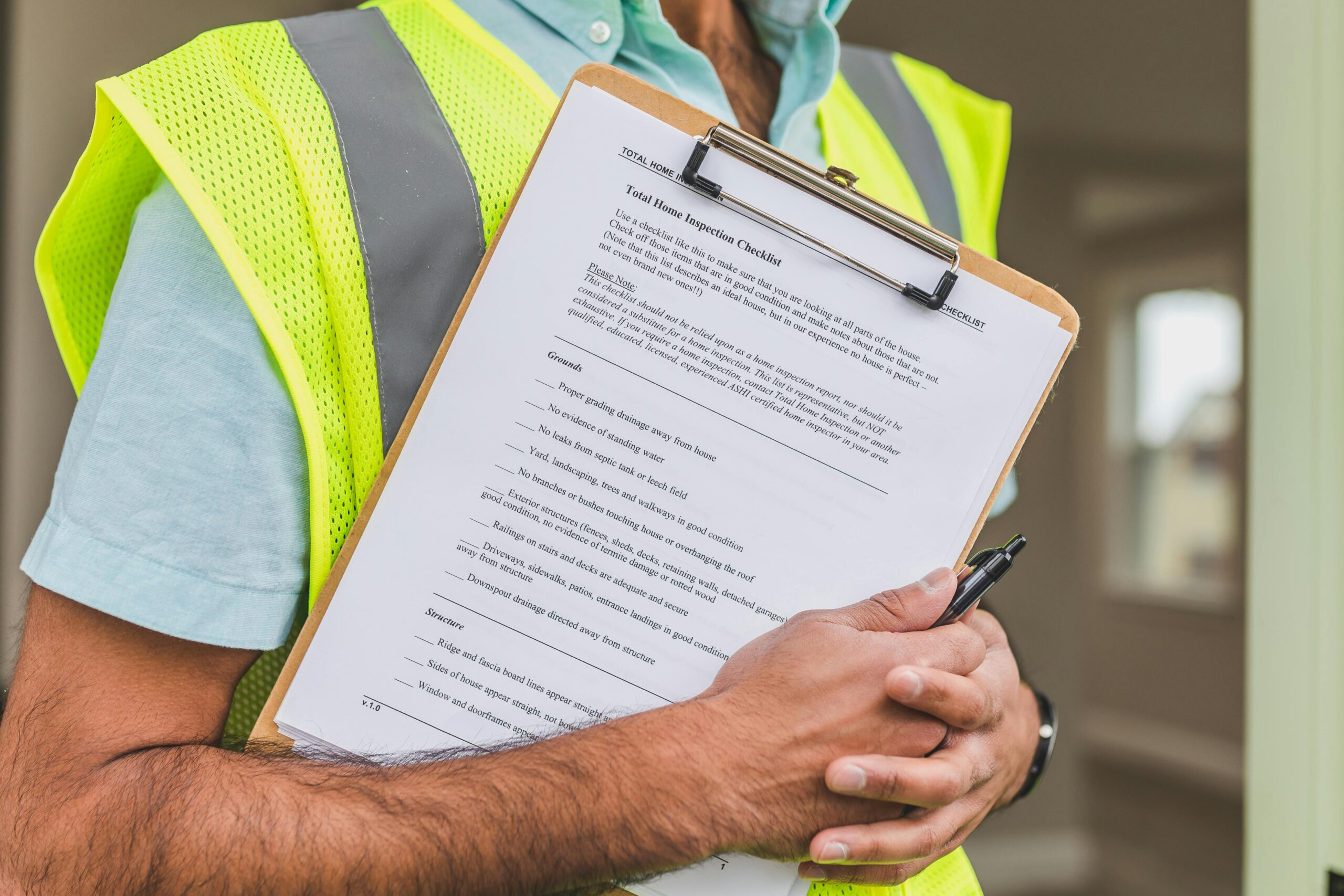 hud-renovation-standards Person wearing a safety vest holding a clipboard with a “Total Home Inspection Checklist” document following going a hud renovation standard