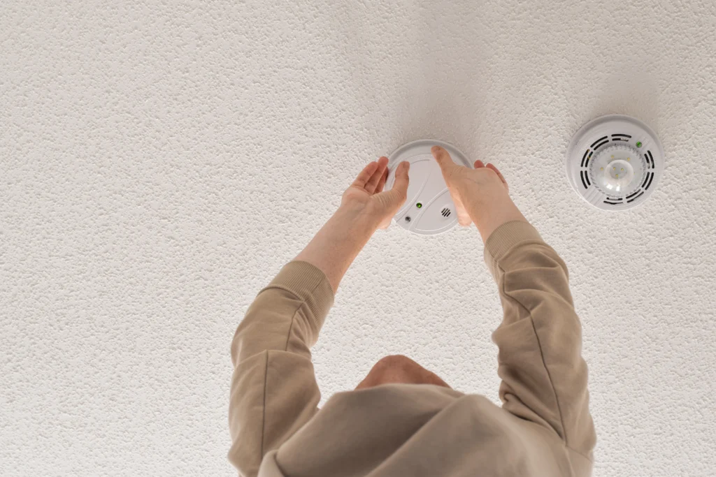 Technician testing smoke detector to meet updated HUD and NSPIRE inspection requirements